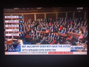 Rep Marjorie Taylor Green of GA (in red) looming behind McCarthy seated at the table in the centre.